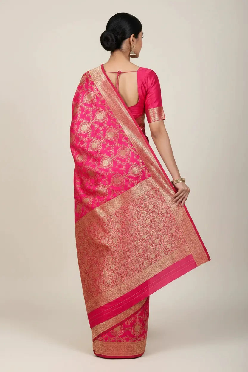 Woman wearing a pink saree with gold patterns on a beige background