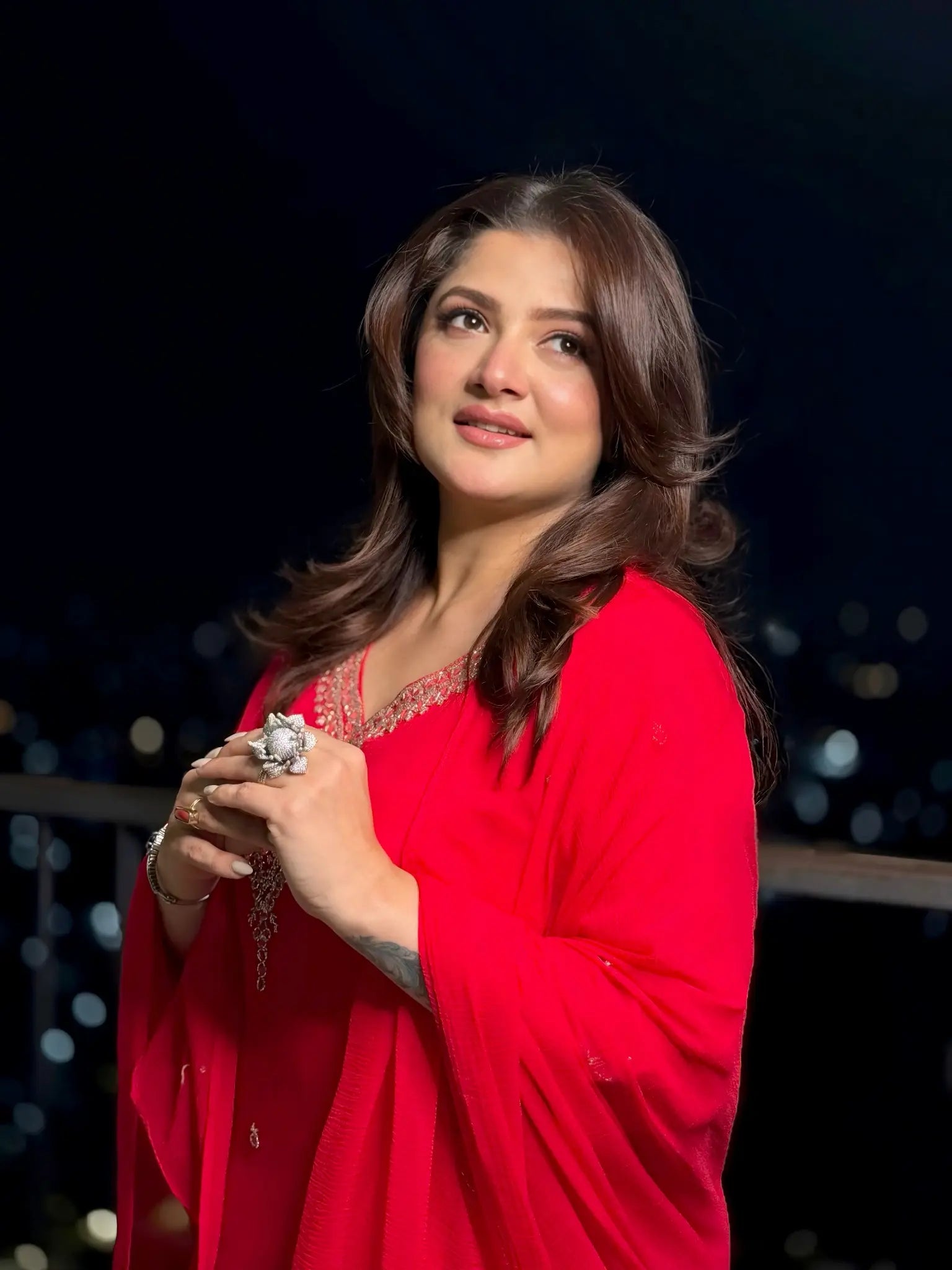 Woman in a red outfit holding a decorative item against a dark background