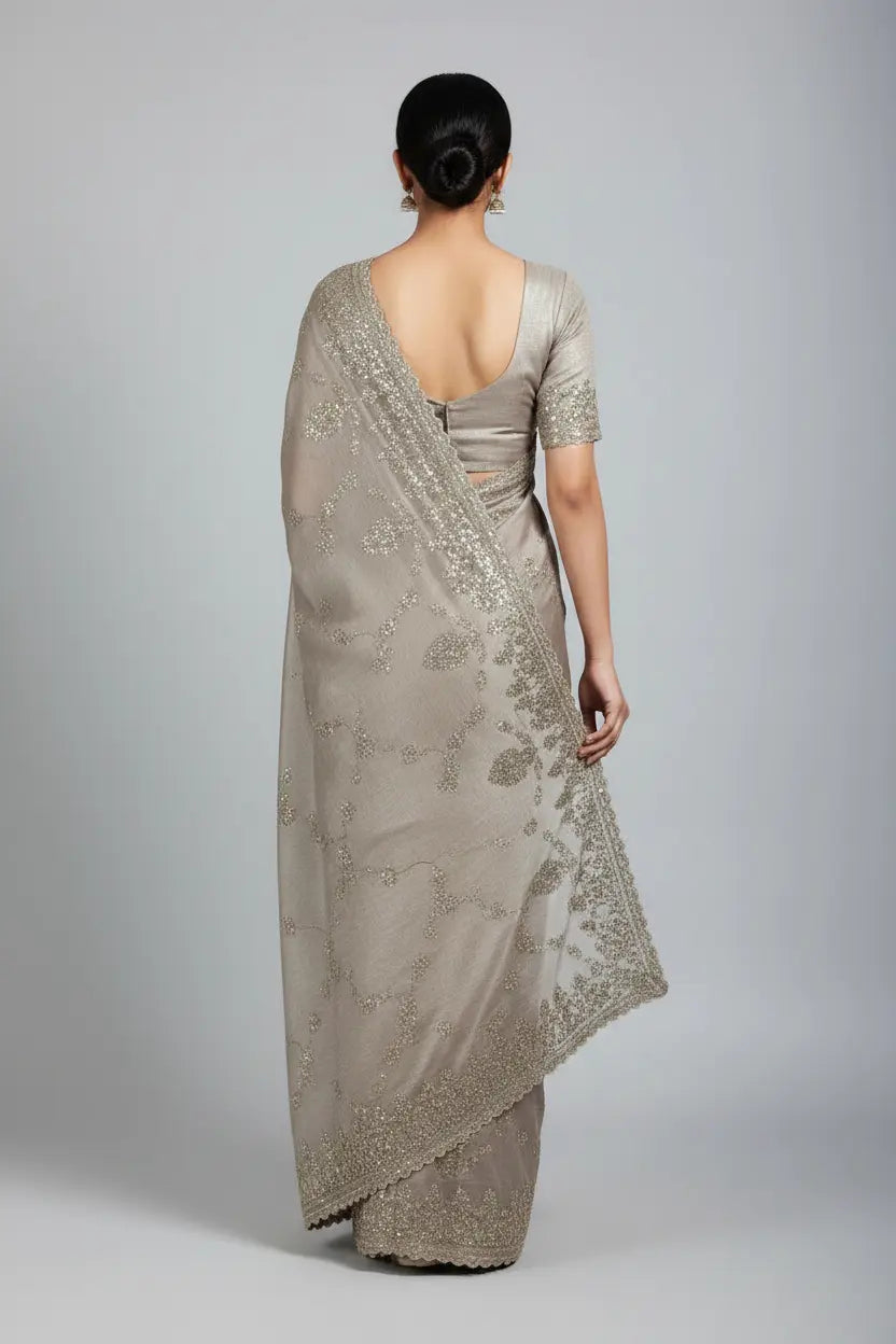 Woman wearing a beige saree with a plain background