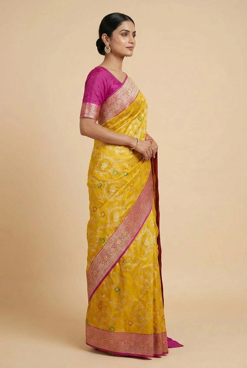 Woman wearing a yellow saree with pink blouse against a beige background