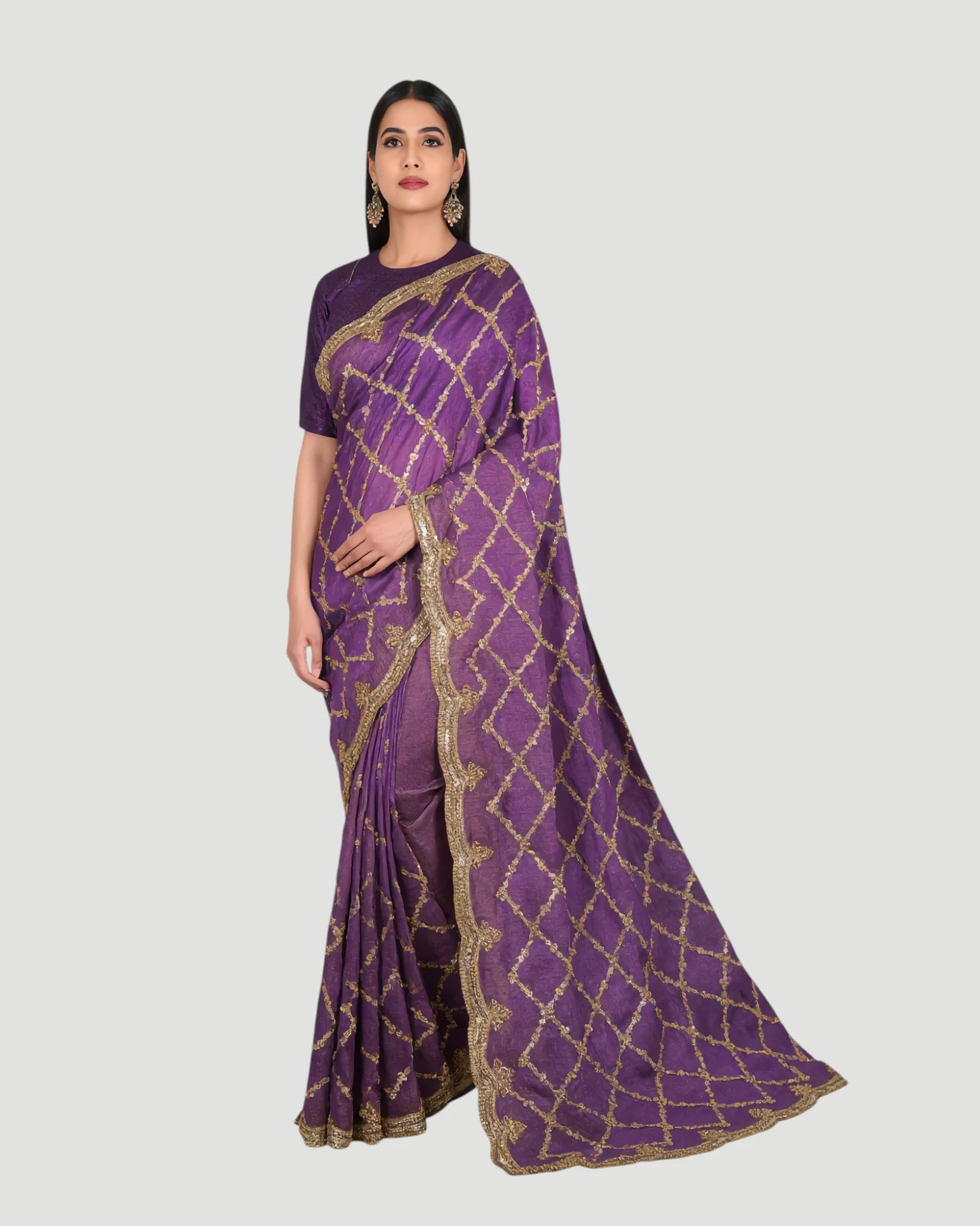 Woman wearing a purple saree with gold patterns on a light gray background