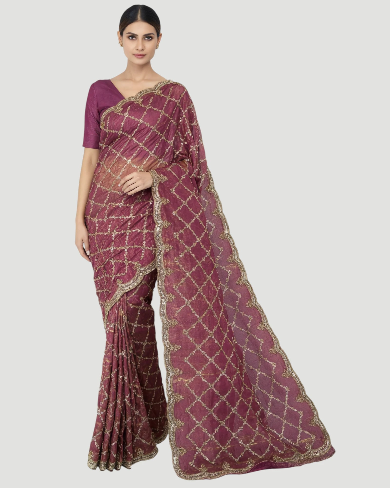 Woman wearing a maroon saree with gold patterns on a white background