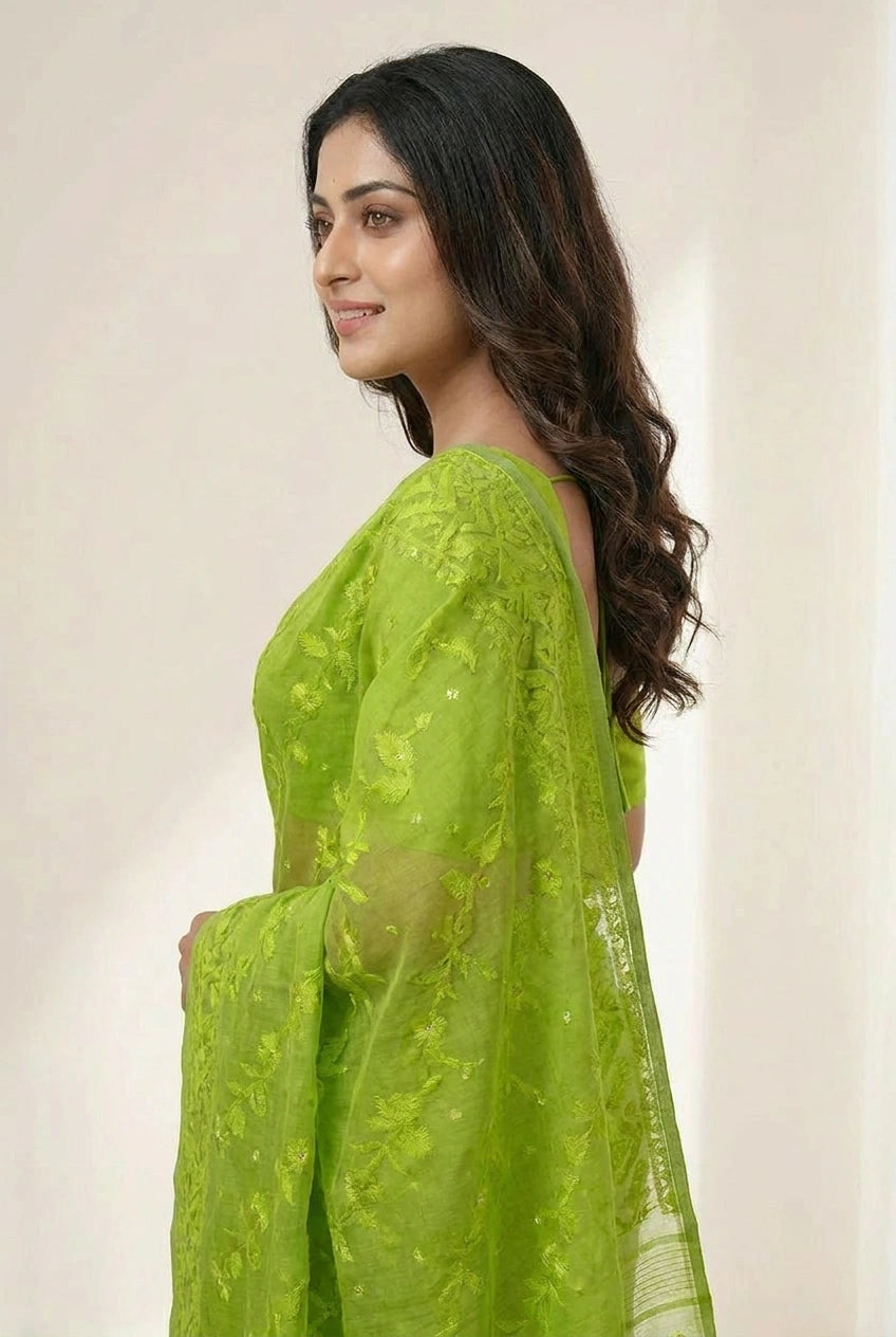 Woman wearing a green saree with a plain background