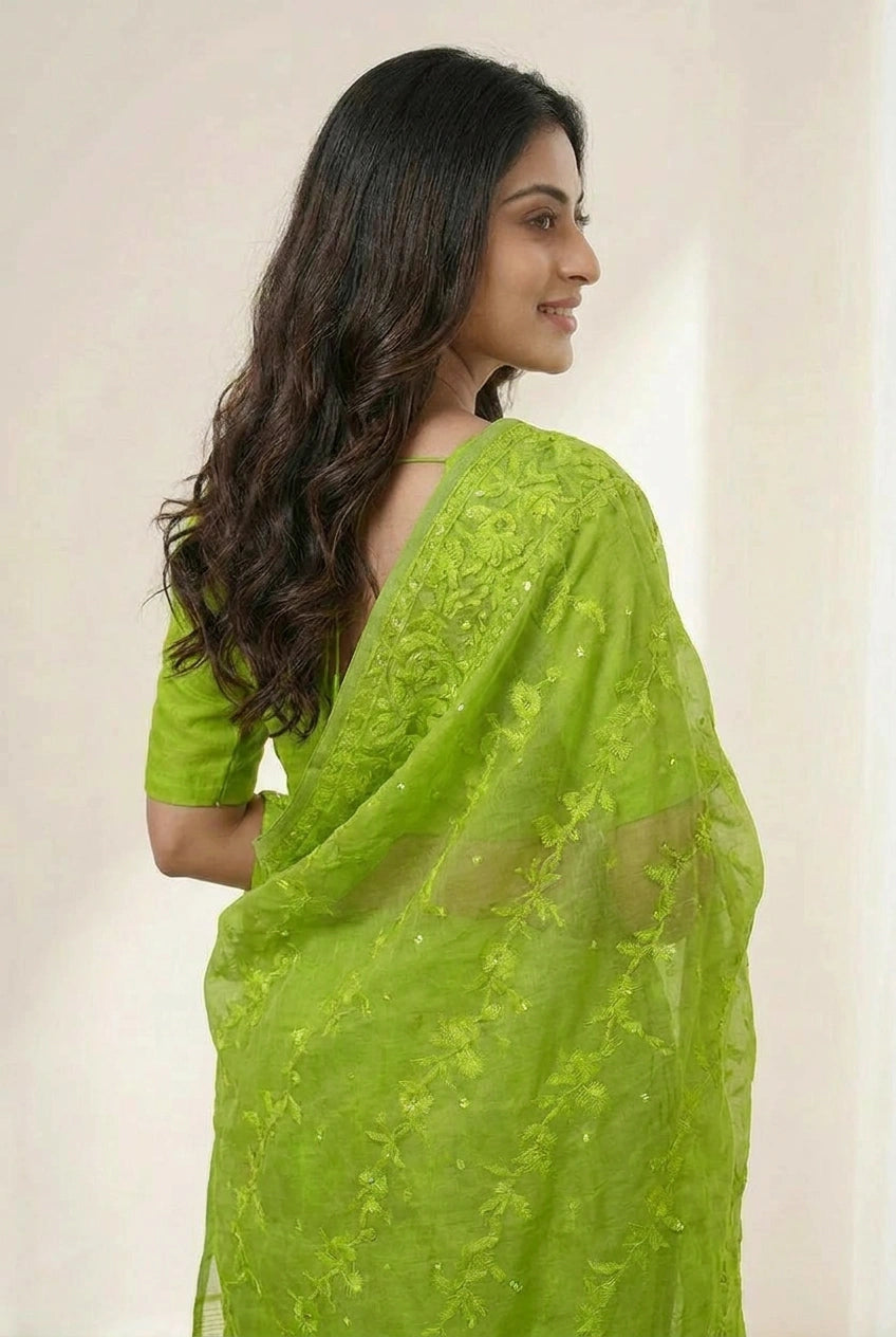 Woman wearing a green saree with a plain background