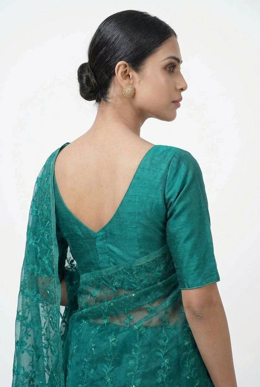 Woman wearing a green saree with a plain background