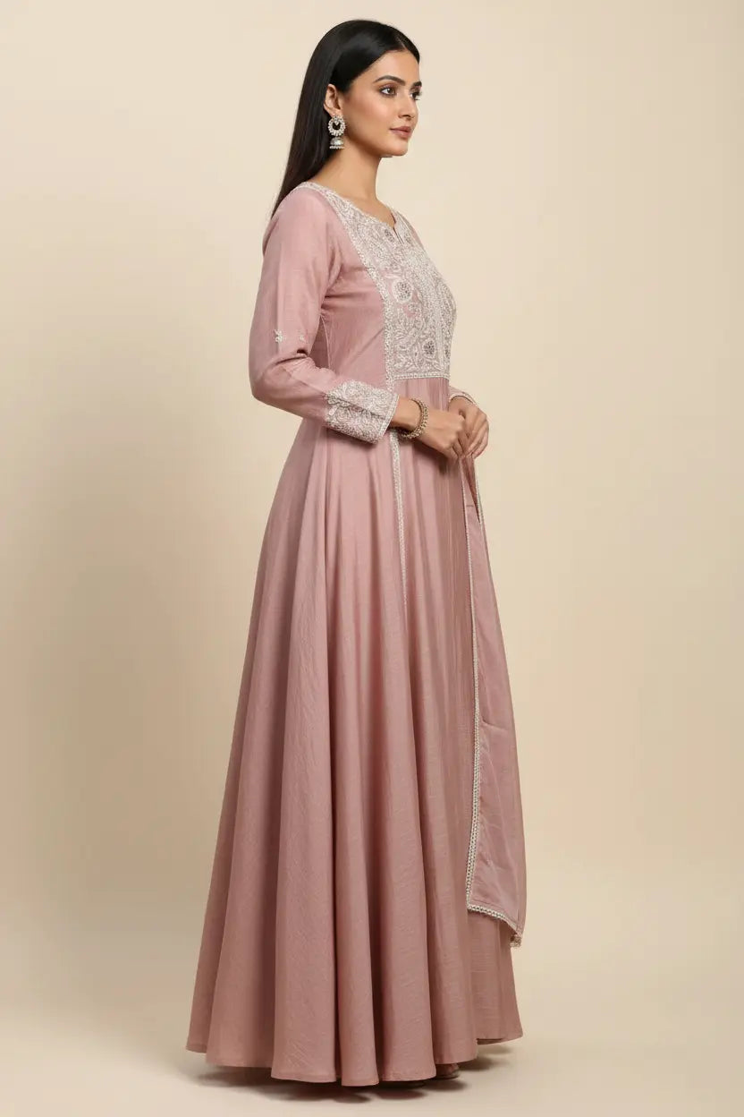 Woman wearing a pink anarkali suit with white embroidery on a beige background