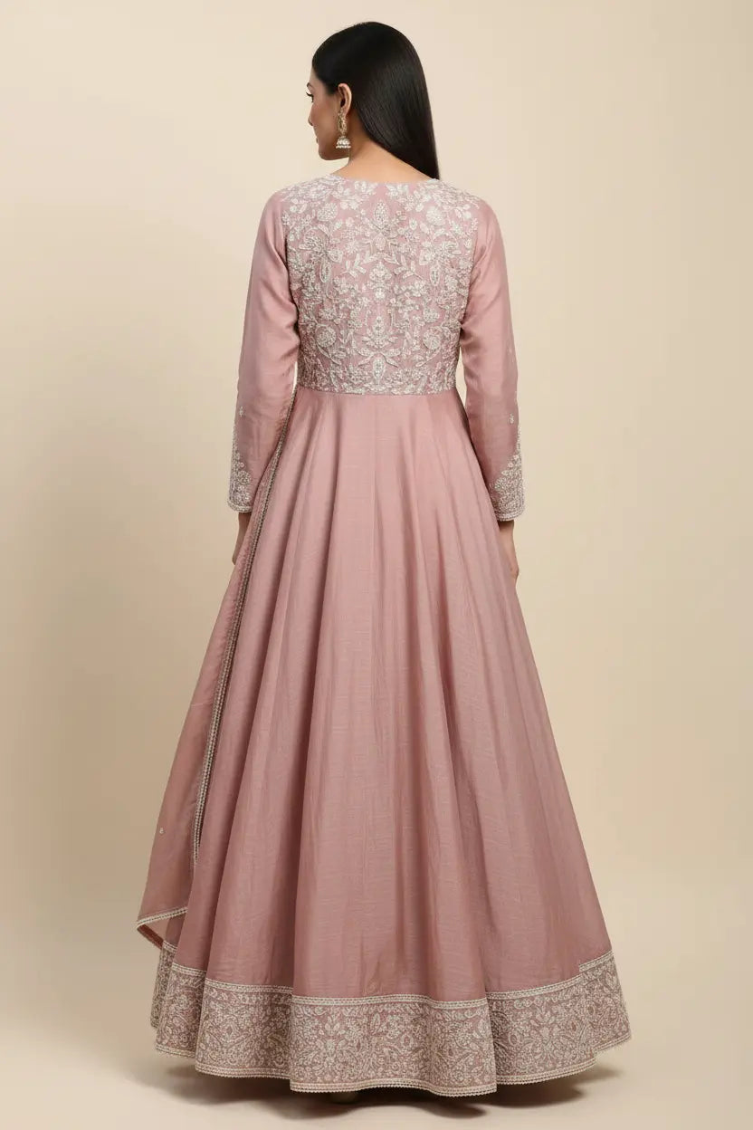 Pink anarkali suit with intricate embroidery on a beige background
