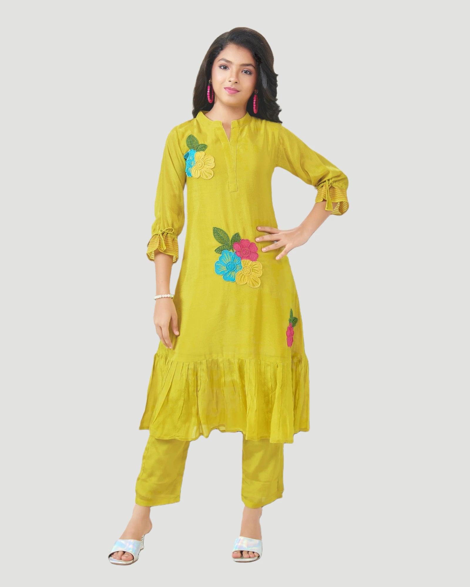 Woman wearing a yellow outfit with floral embroidery on a white background