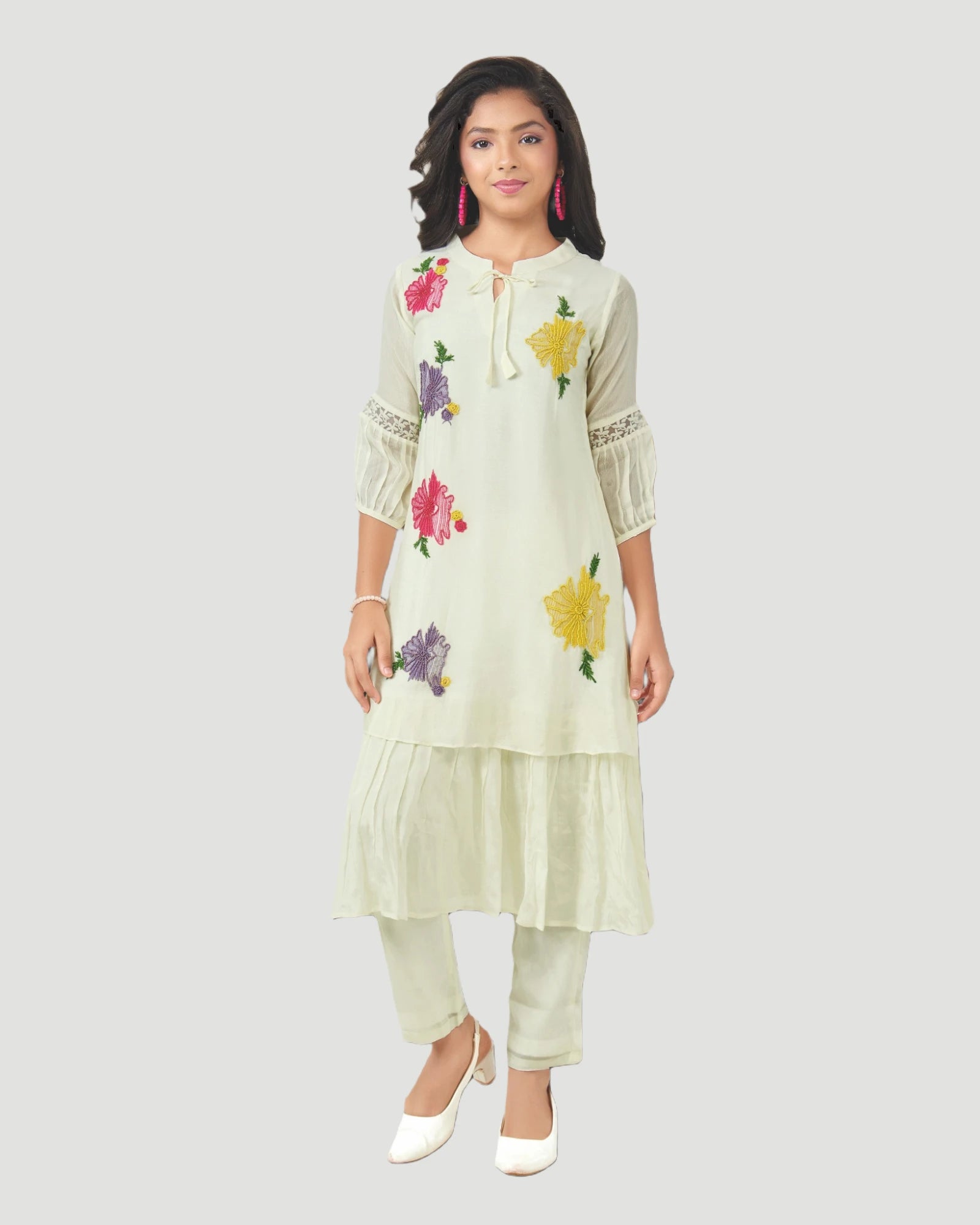 Woman wearing a light green embroidered outfit on a white background