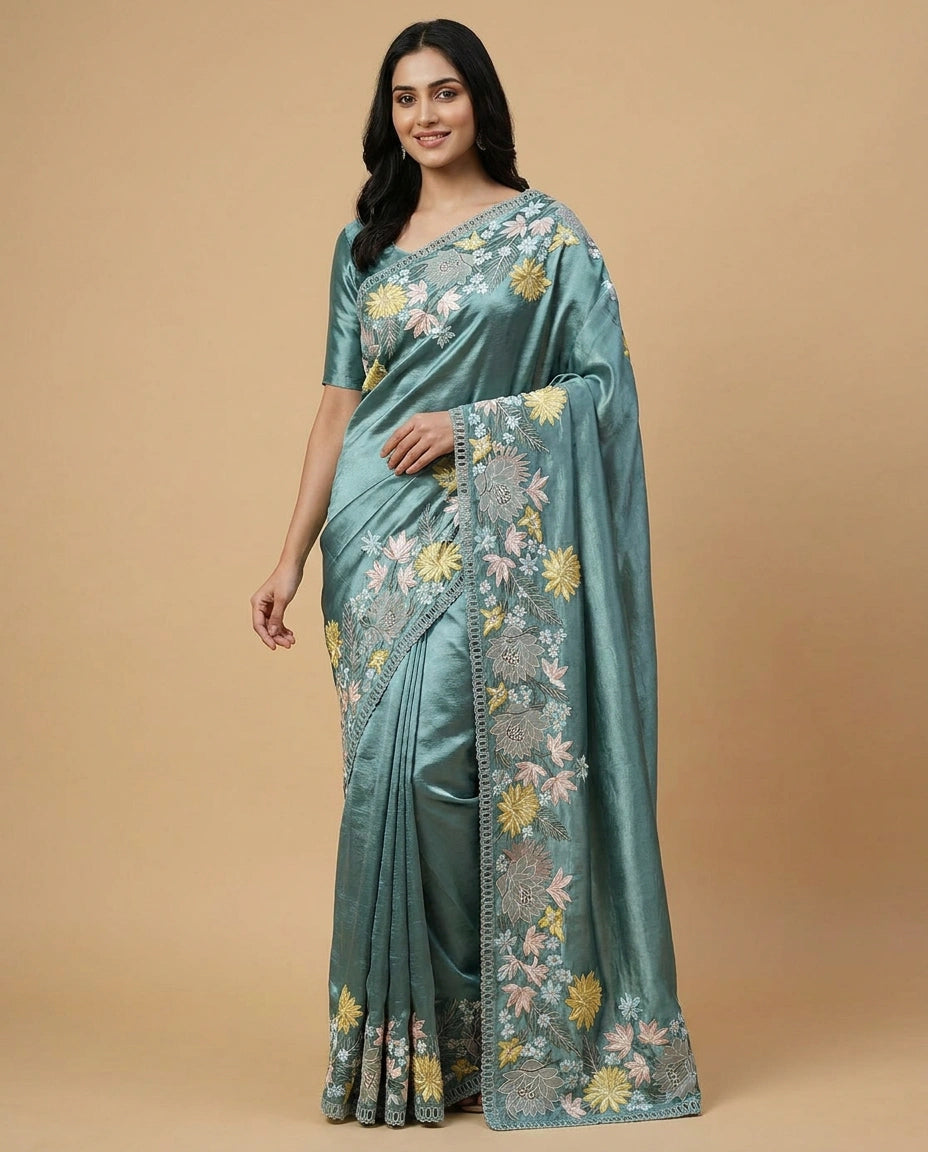 Woman wearing a teal saree with floral patterns on a beige background