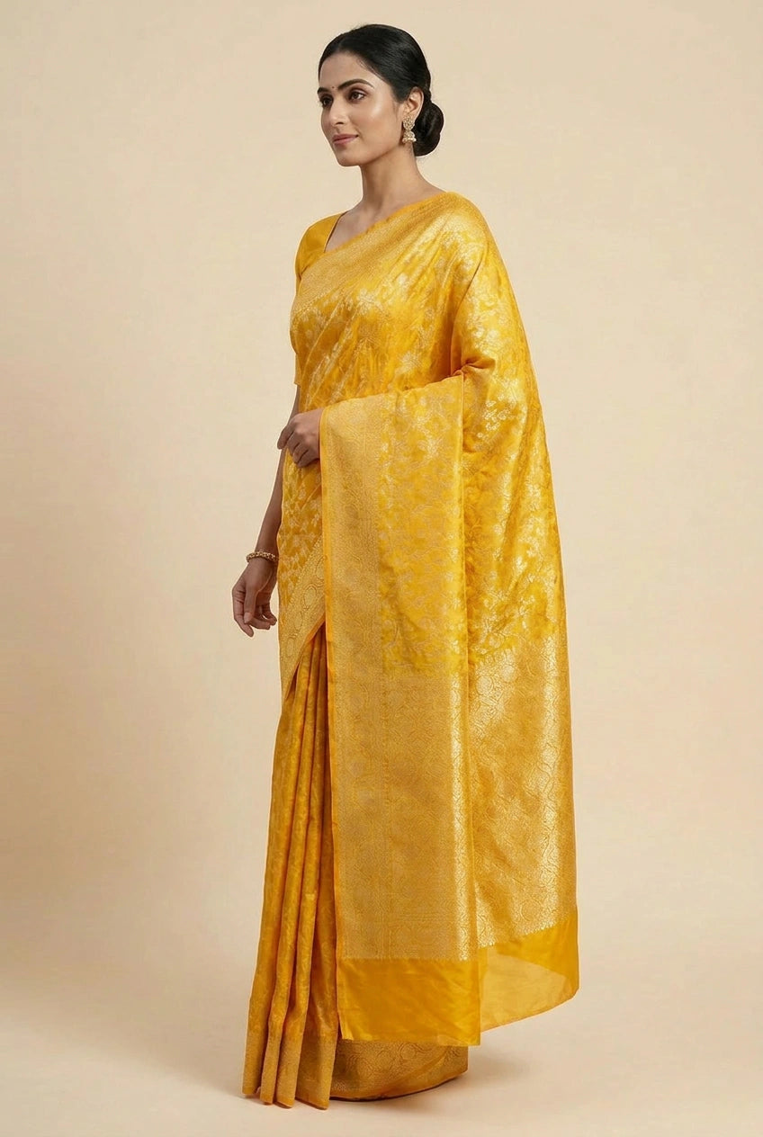 Woman wearing a yellow saree with a plain background