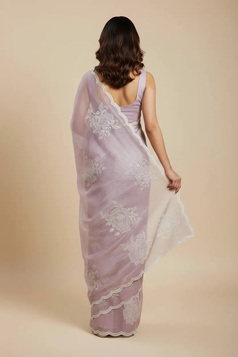 Woman wearing a light purple saree with white lace details on a beige background