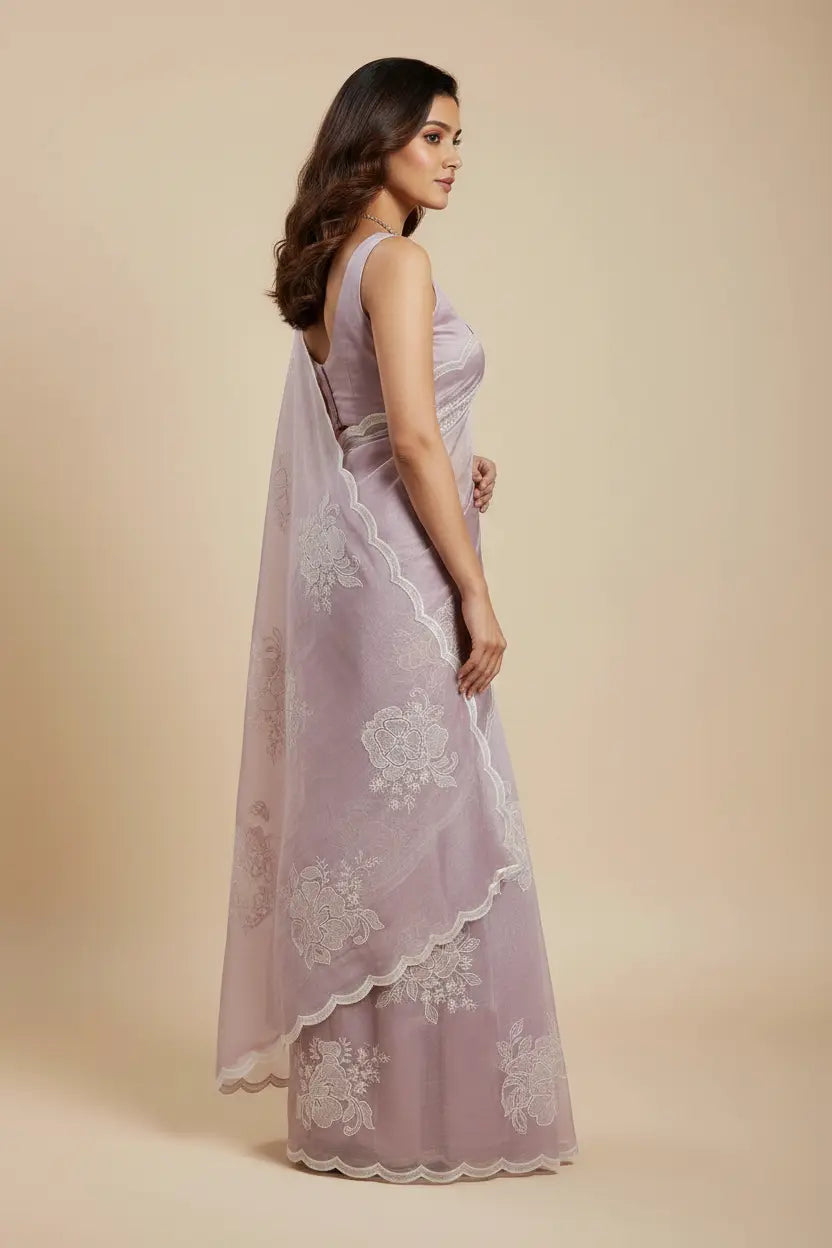 Woman wearing a light purple saree with white floral patterns on a beige background