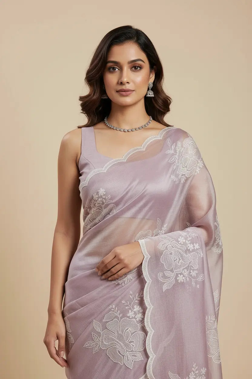 Woman wearing a light purple saree with white lace details on a beige background