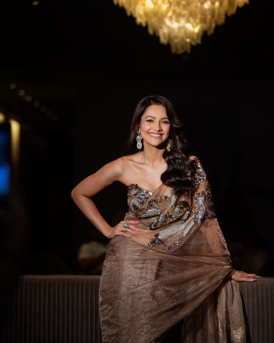 Woman in a glamorous dress posing indoors with a blurred background