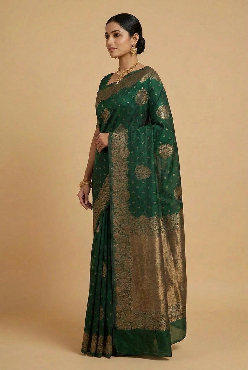 Woman wearing a green saree with gold patterns on a beige background