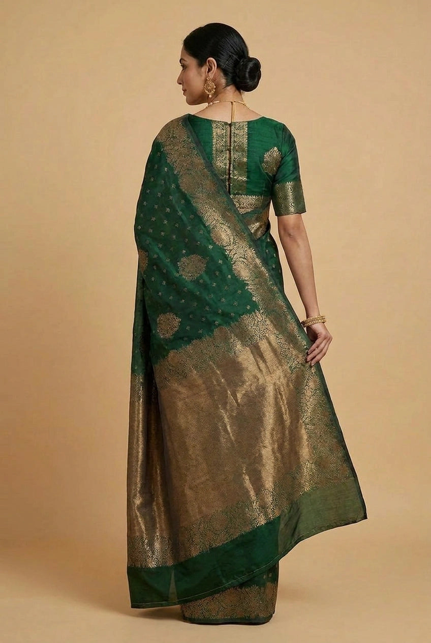 Woman wearing a green and gold saree on a beige background