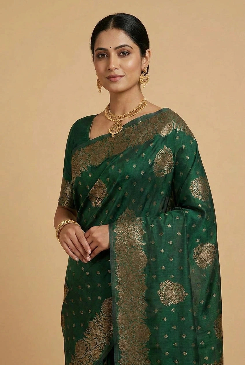 Woman wearing a green saree with gold patterns on a beige background