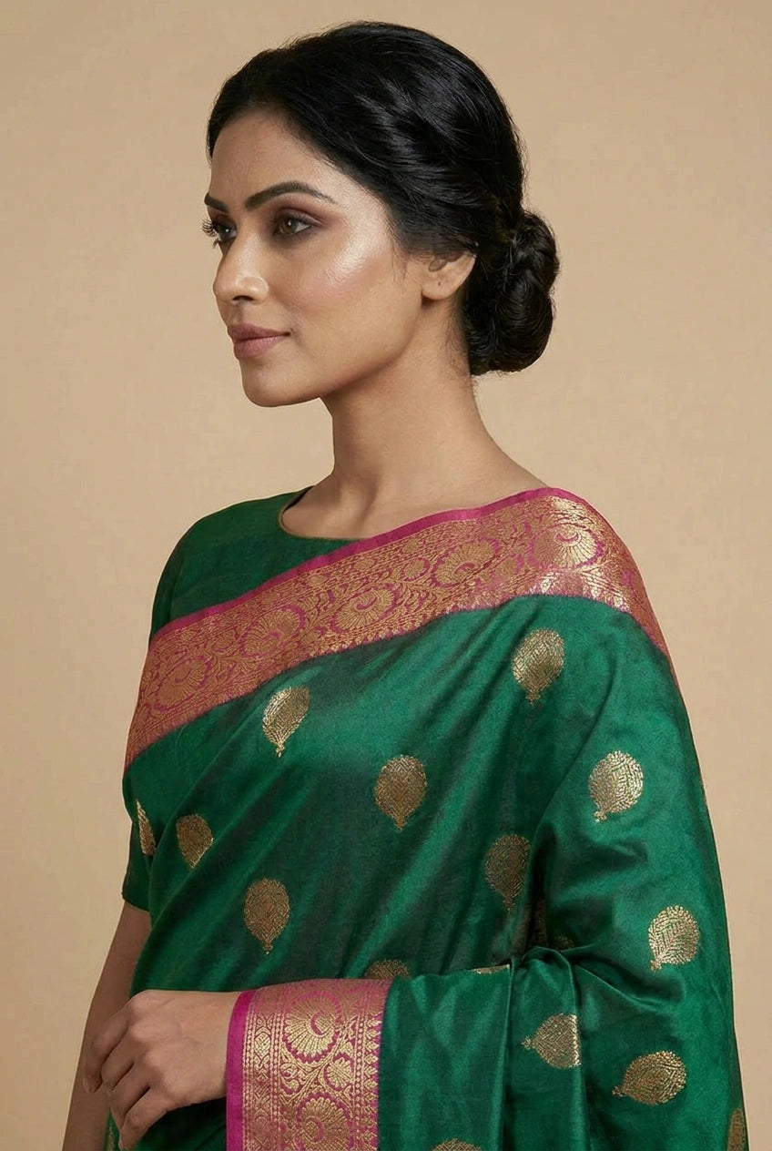Woman wearing a green saree with gold patterns on a beige background