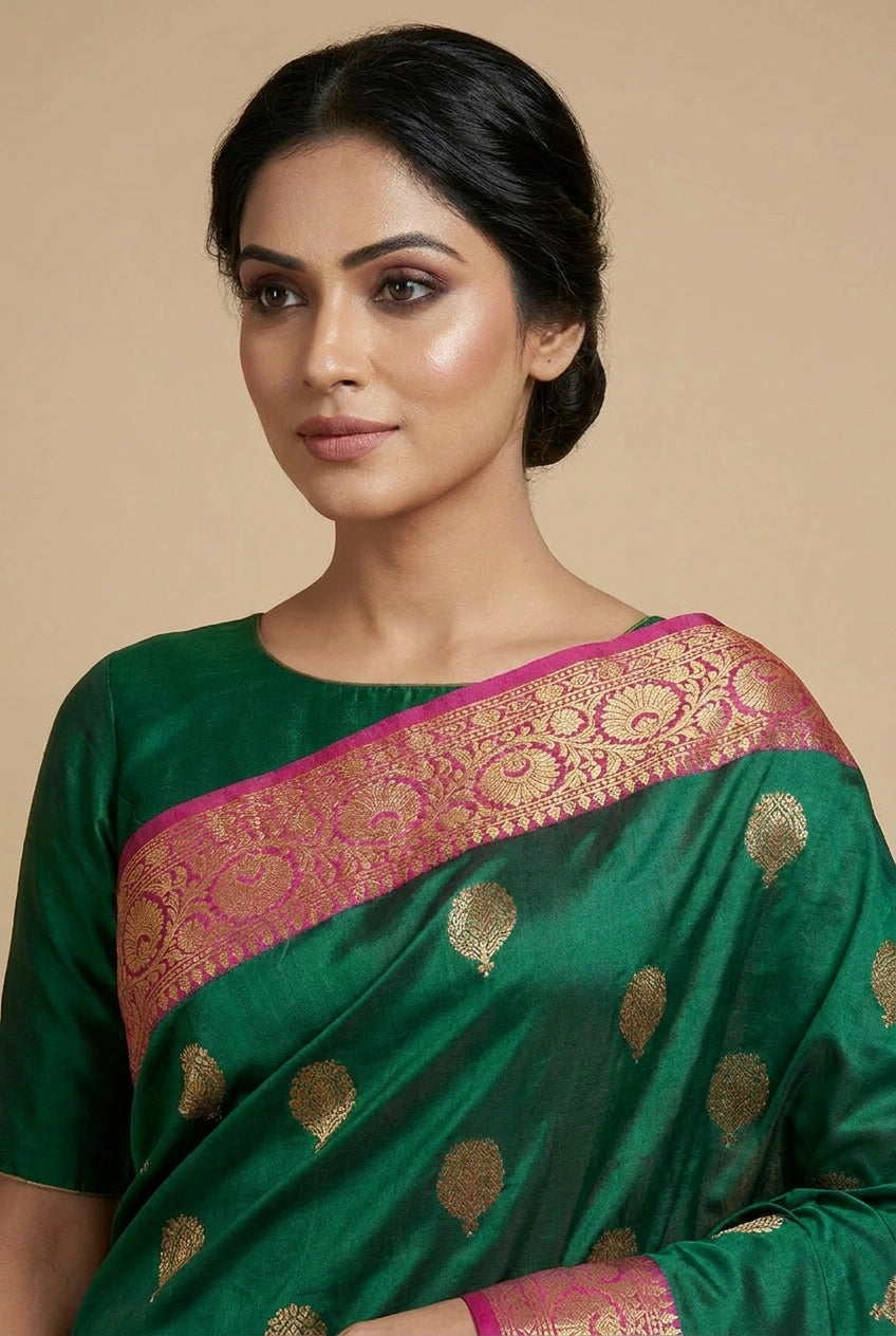 Woman wearing a green saree with gold patterns on a beige background