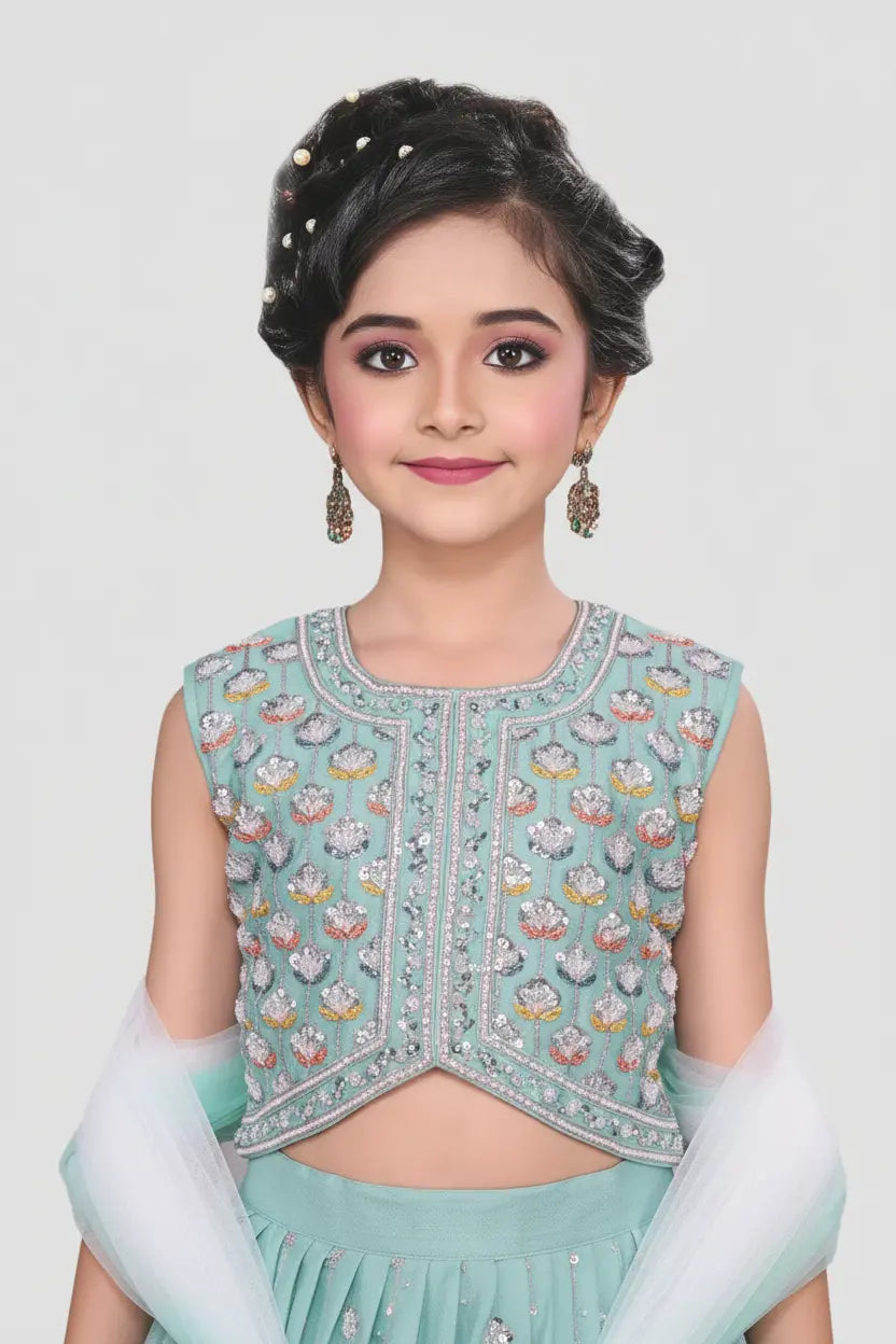 Young girl wearing a light blue embroidered top and skirt against a white background