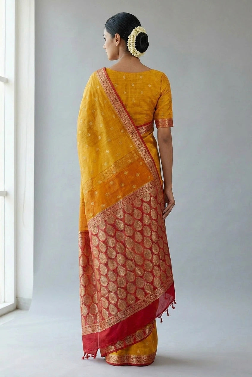 Woman wearing a yellow and red saree standing in a well-lit room.