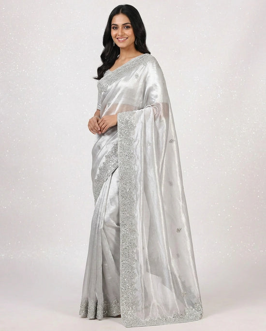 Woman wearing a silver saree with a white background