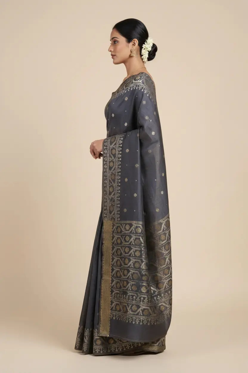Woman wearing a dark gray saree with intricate patterns on a beige background