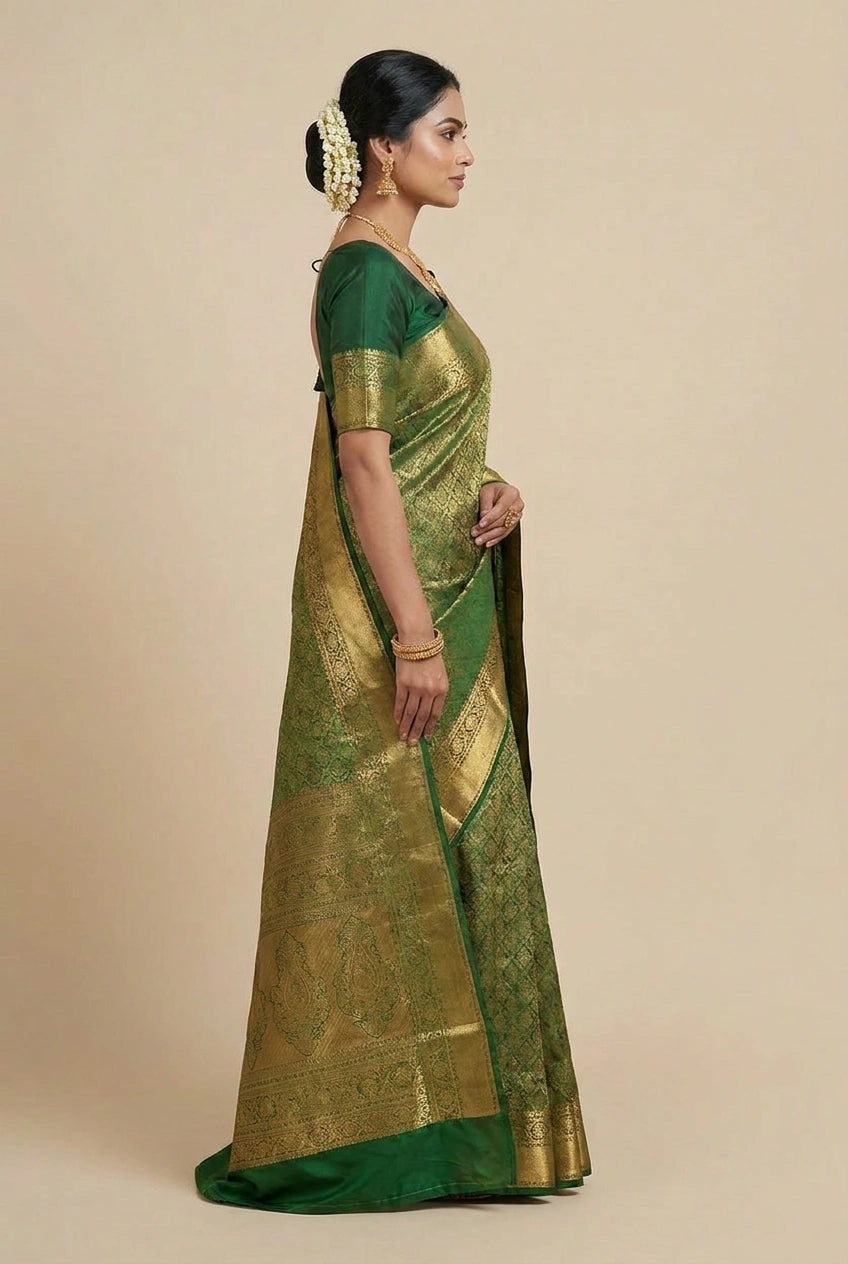 Woman wearing a green saree with gold patterns on a beige background