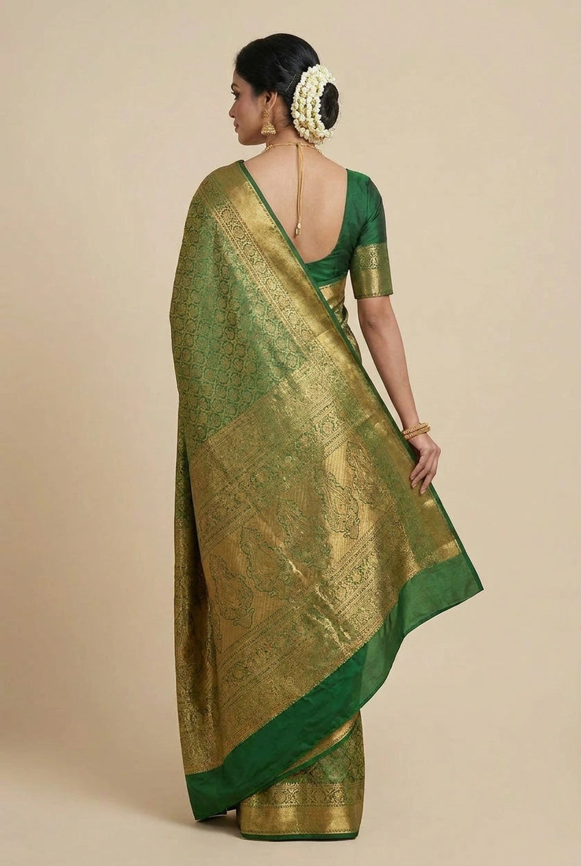 Woman wearing a green saree with a gold border on a beige background