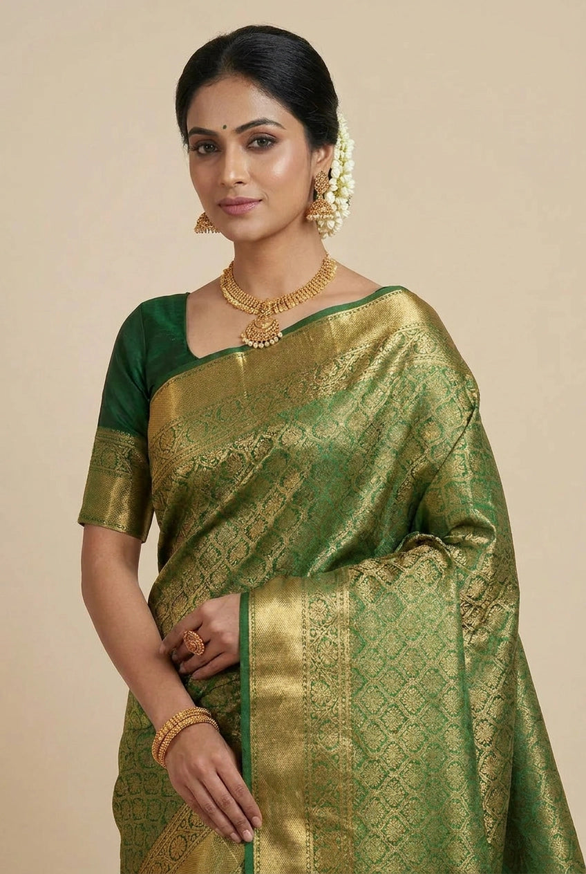 Woman wearing a green and gold saree with jewelry on a beige background