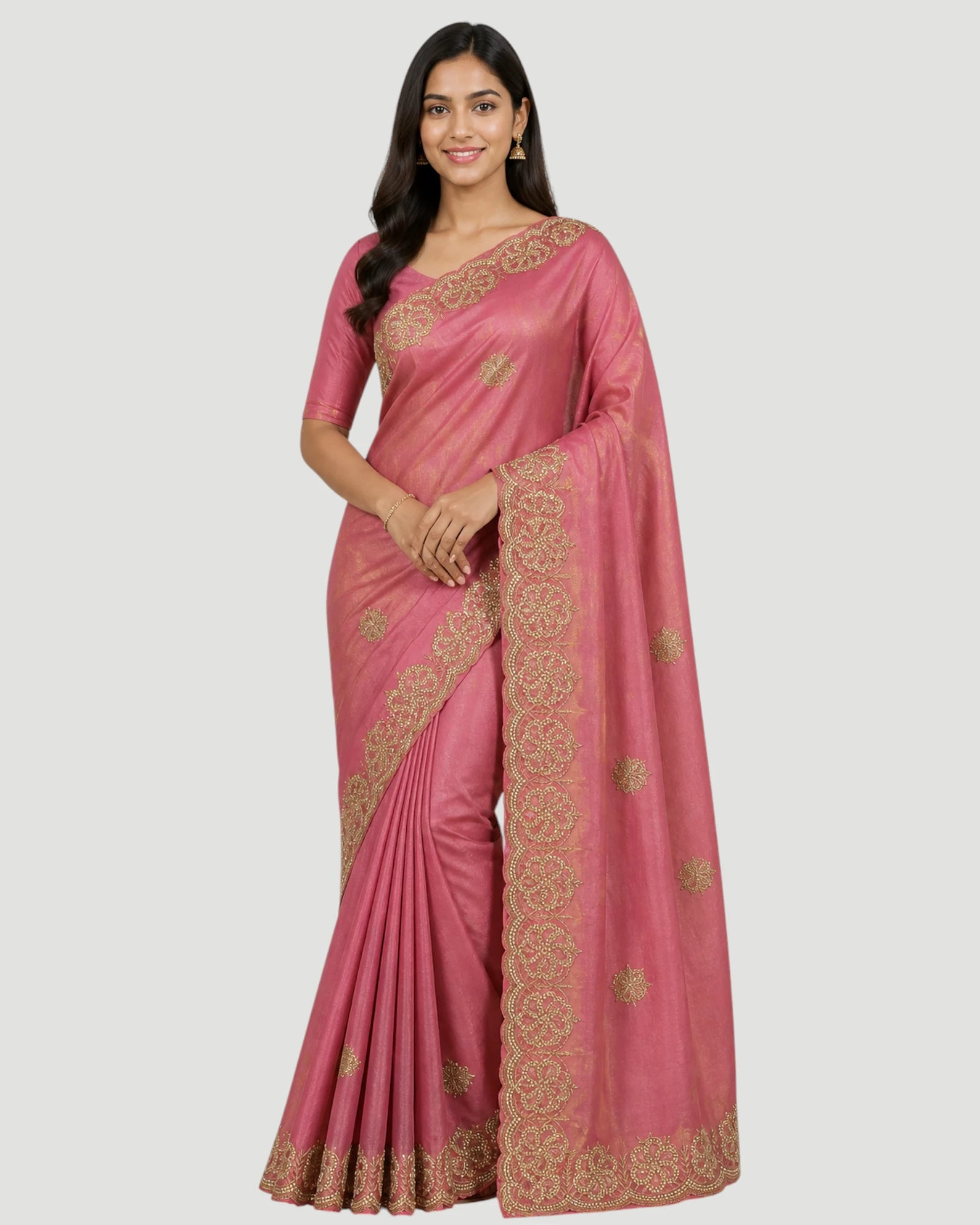Woman wearing a pink saree with gold embroidery on a white background