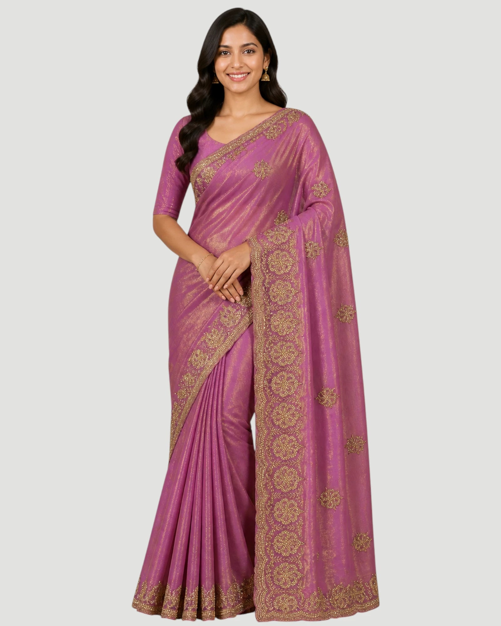 Woman wearing a pink saree with gold patterns on a white background