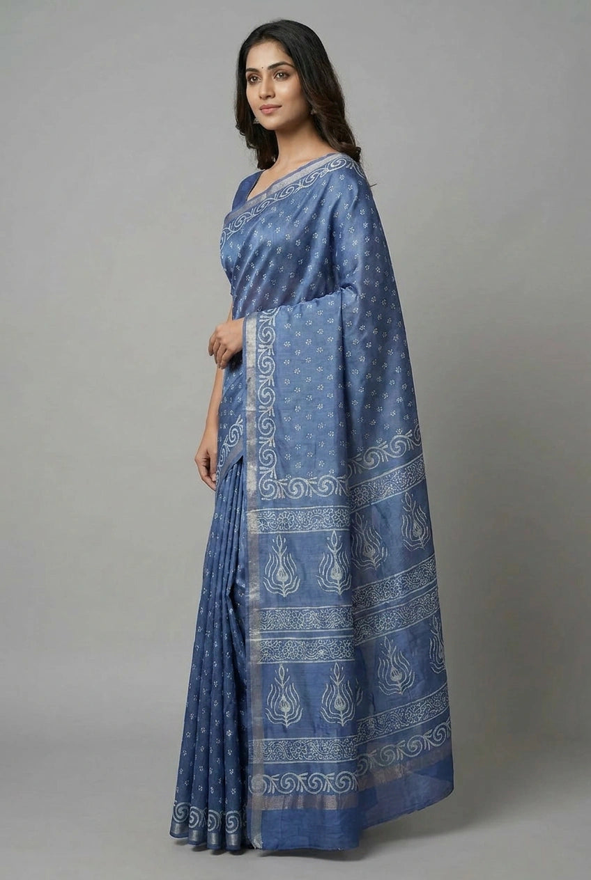 Woman wearing a blue saree with white patterns on a gray background