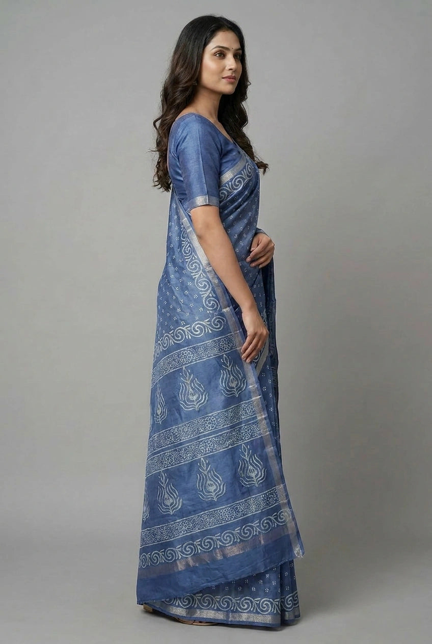 Woman wearing a blue saree with white patterns on a gray background