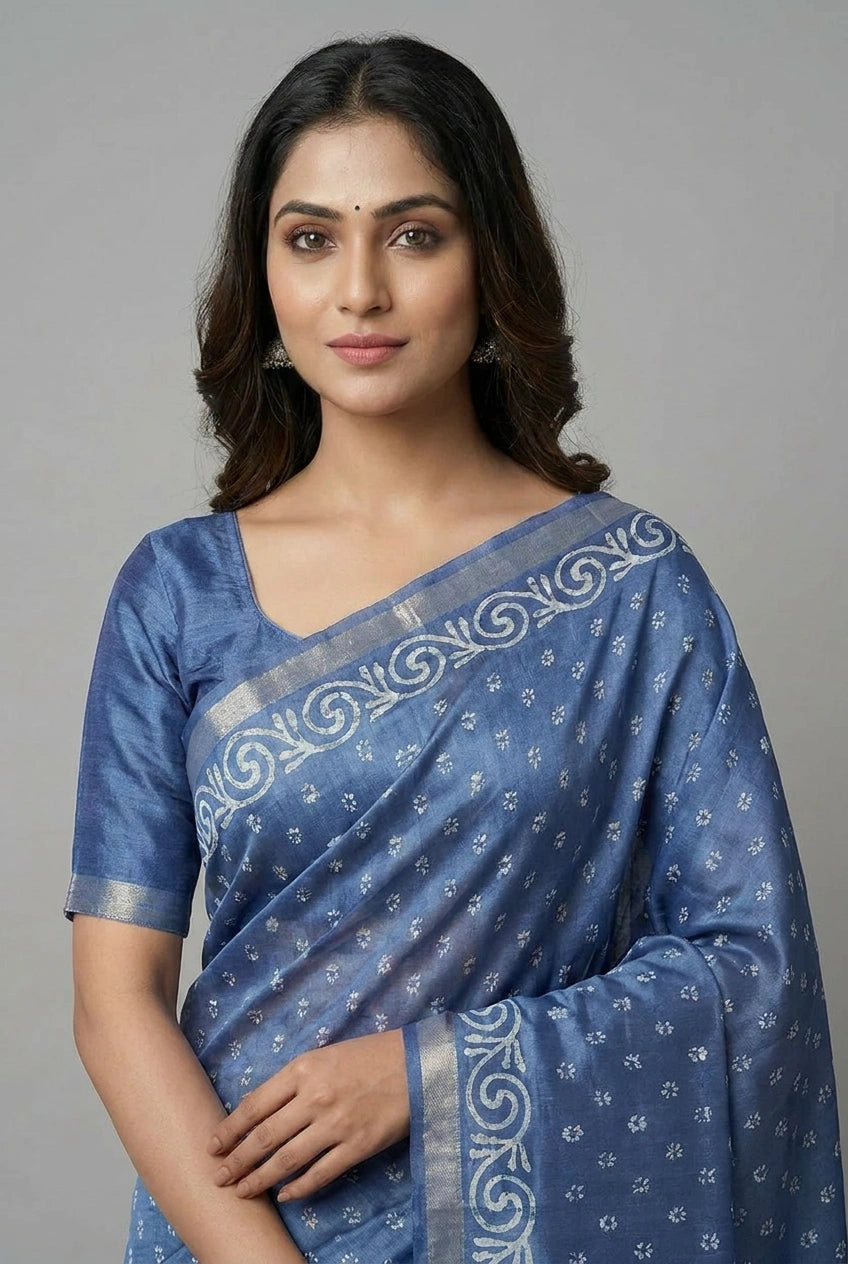 Woman wearing a blue saree with white patterns on a gray background