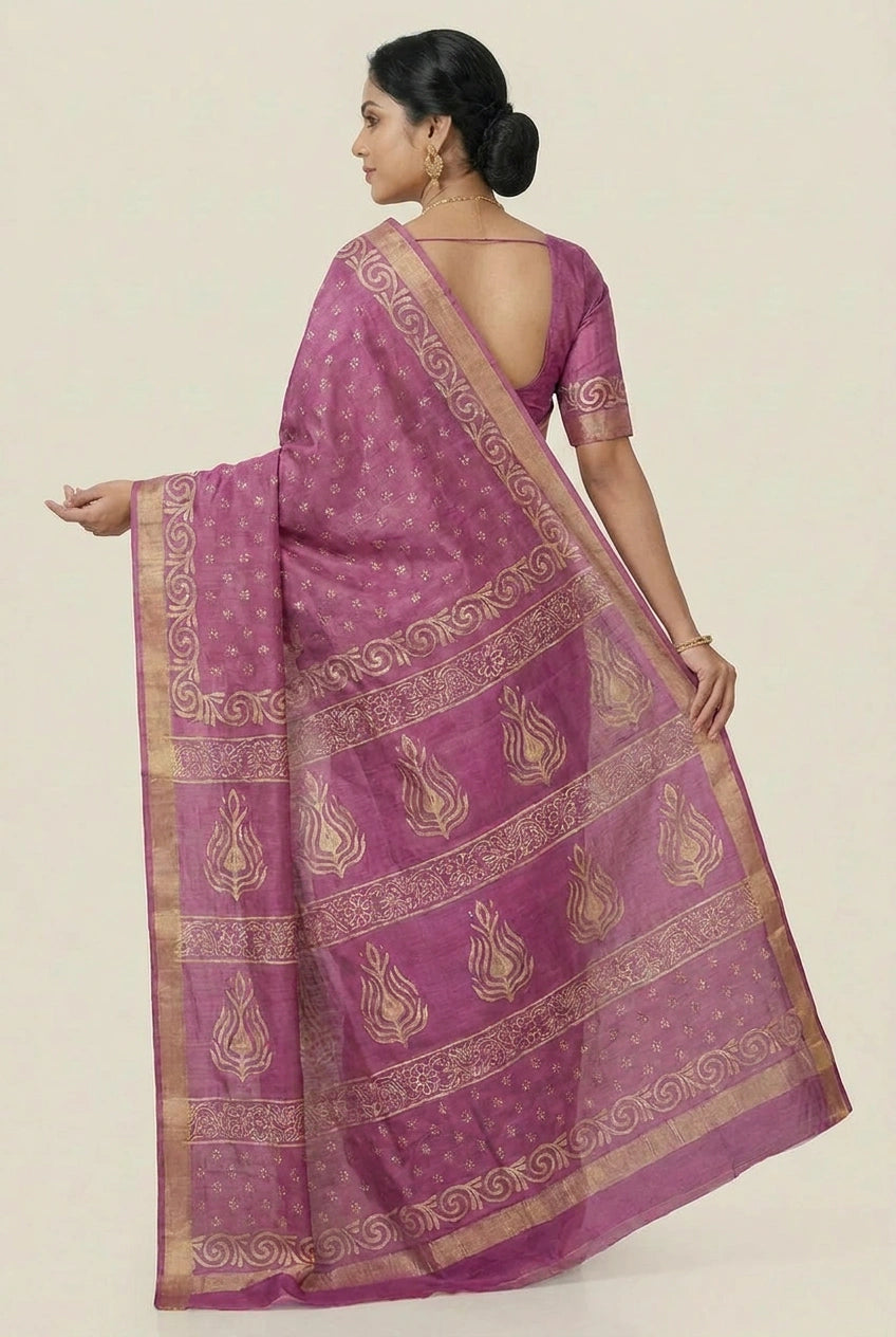 Woman wearing a purple saree with gold patterns on a beige background