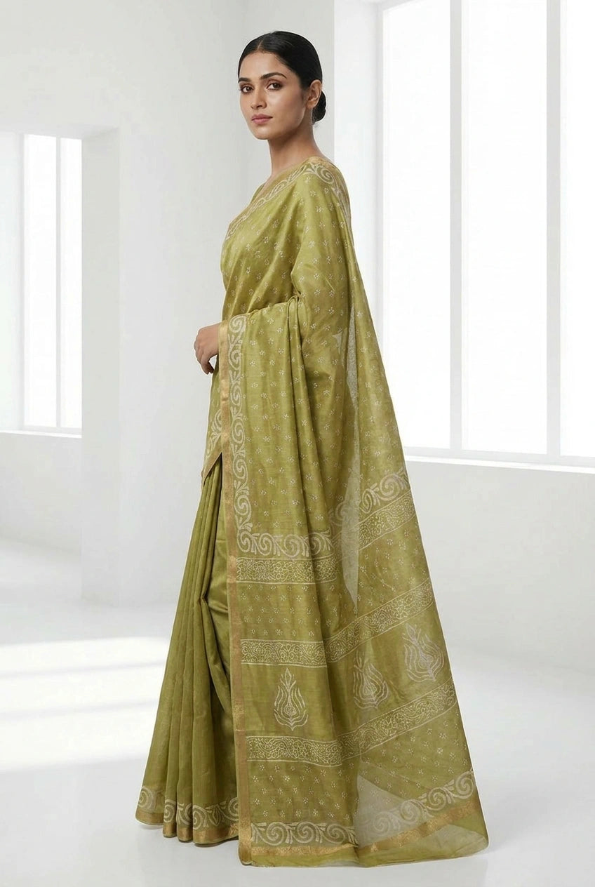 Woman wearing a green saree with white patterns in a minimalistic setting