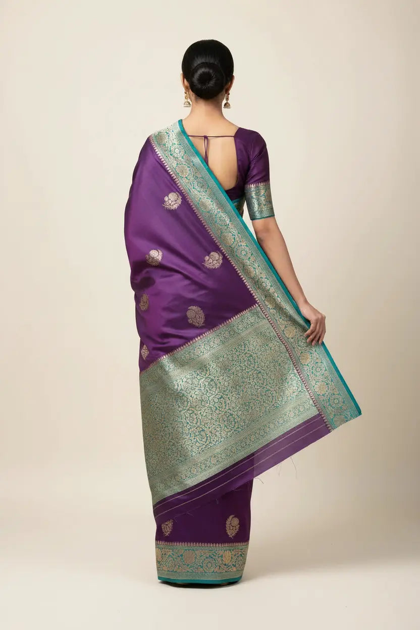 Woman wearing a purple and green saree with a plain background