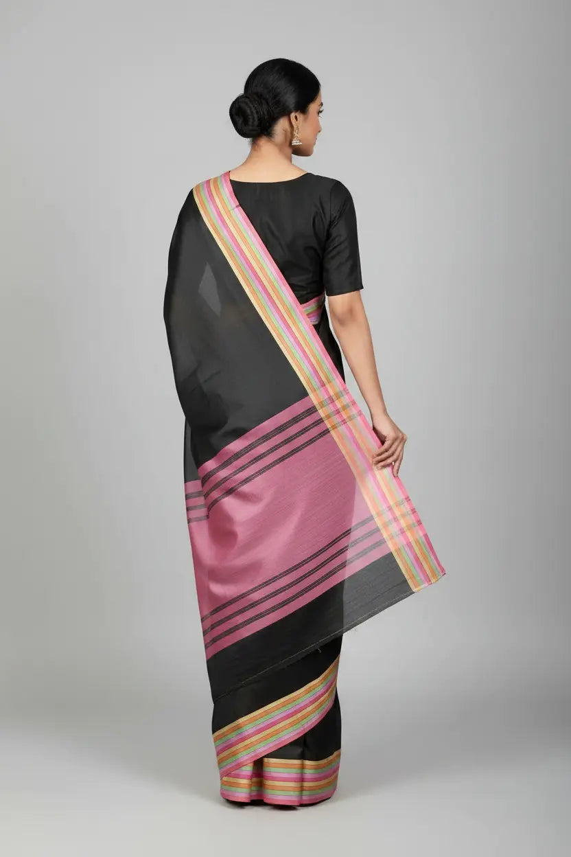 Woman wearing a black saree with pink and gold stripes on a gray background