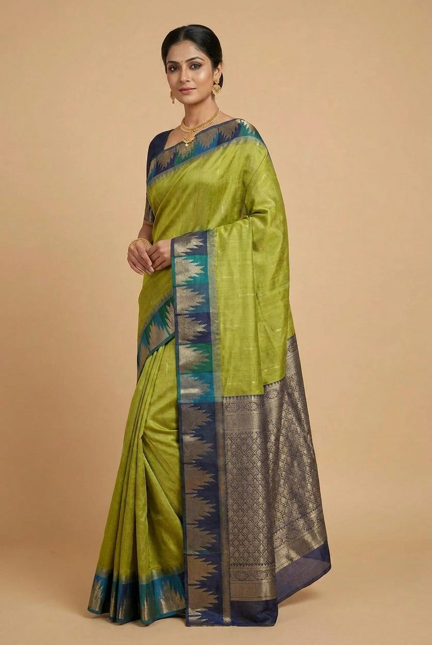 Woman wearing a green saree with a blue and gold border on a beige background