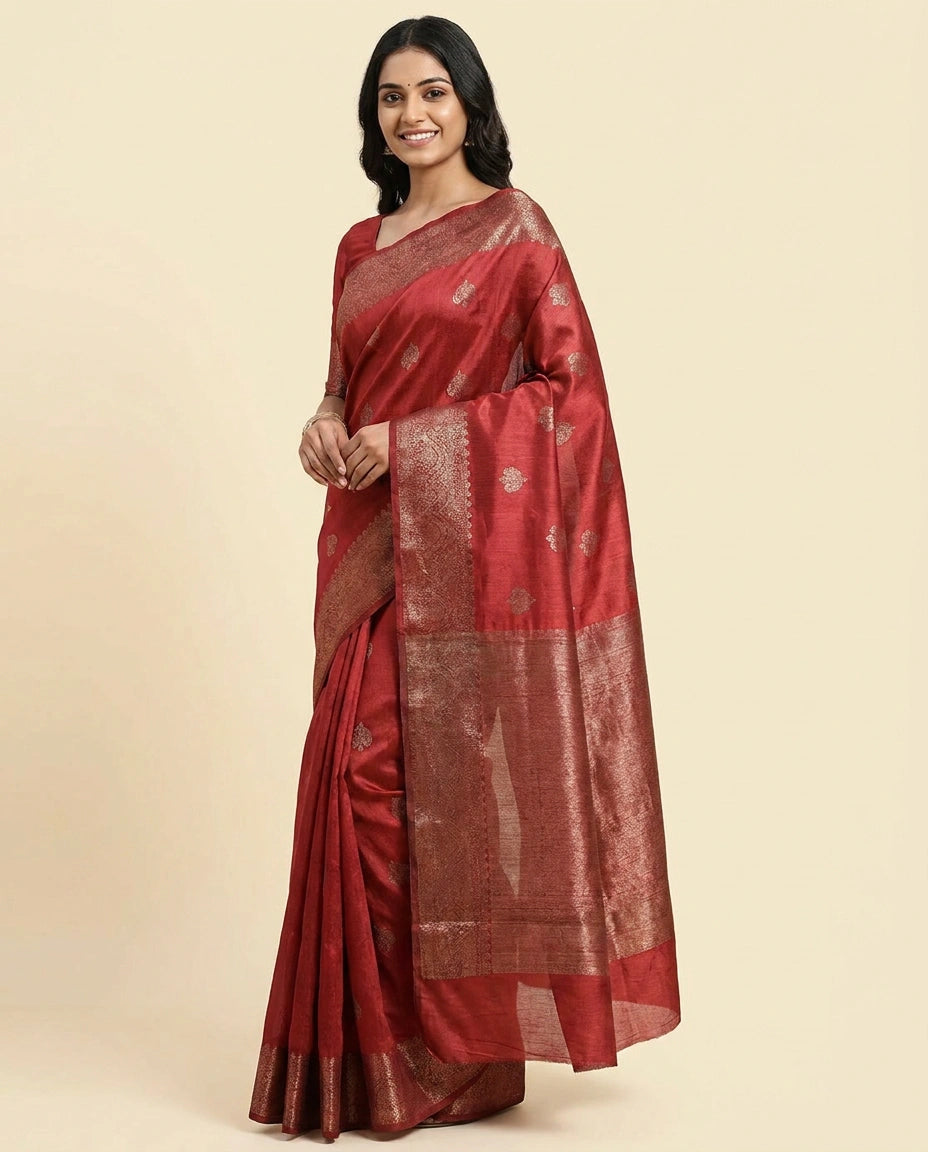 Woman wearing a red saree with gold patterns on a beige background