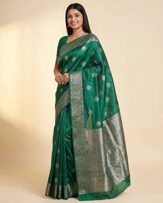 Woman wearing a green saree with silver patterns on a beige background