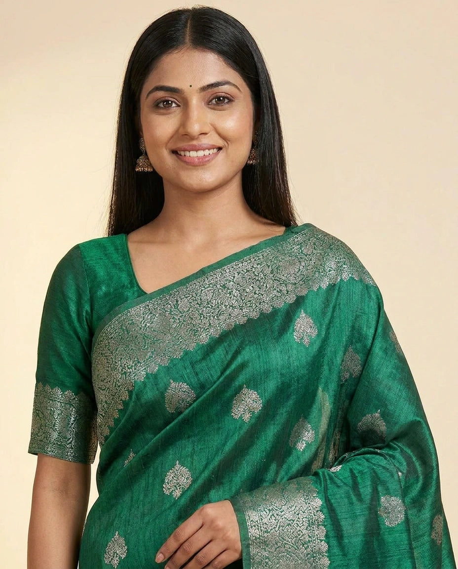 Woman wearing a green saree with silver patterns on a beige background