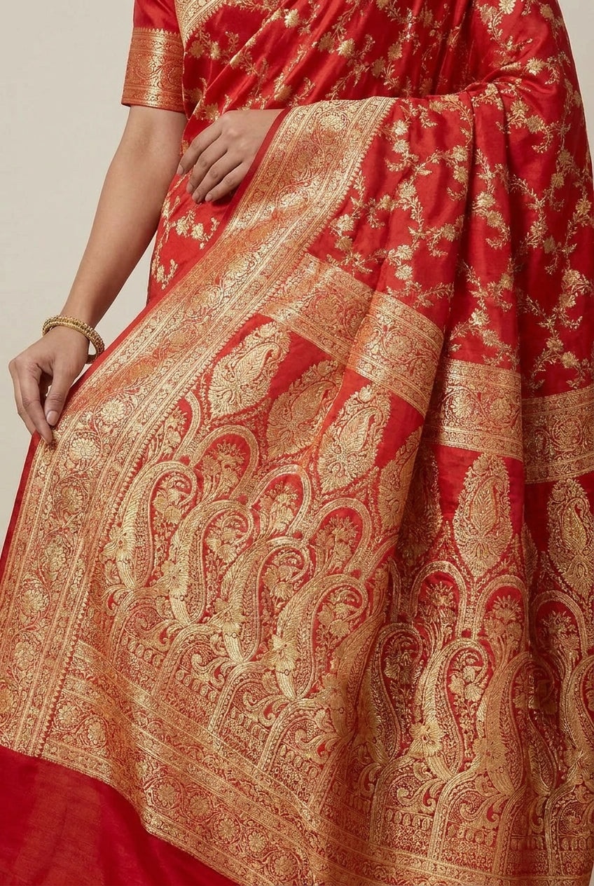Red saree with gold patterns on a neutral background