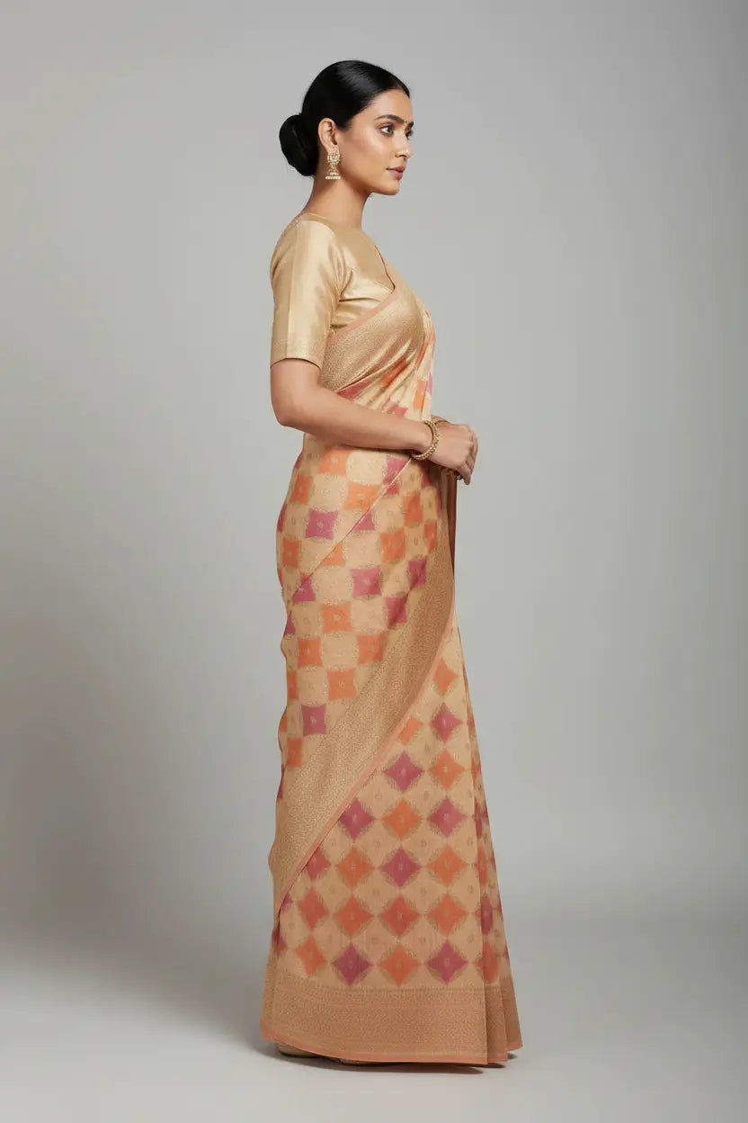 Woman wearing a gold blouse and a patterned beige saree on a plain background