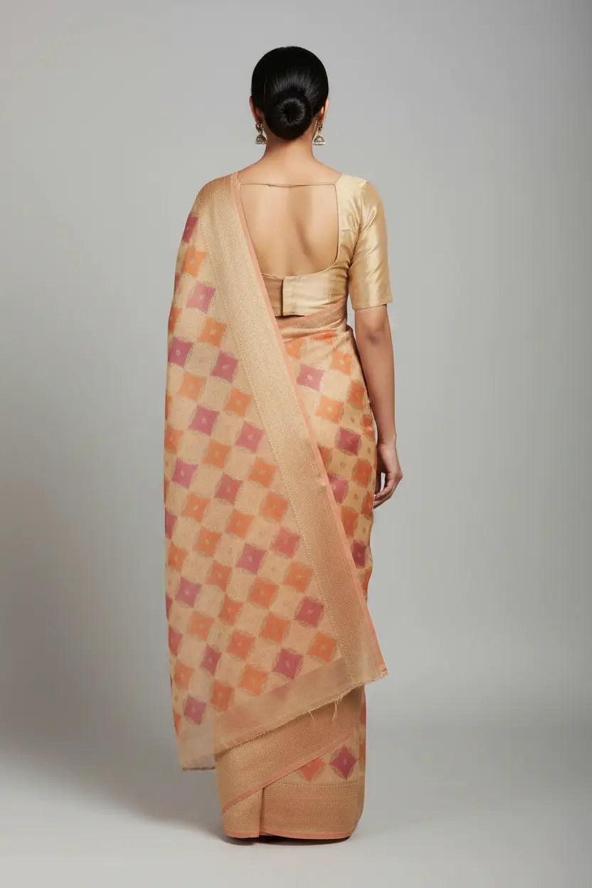 Woman wearing a beige saree with a geometric pattern on a plain background