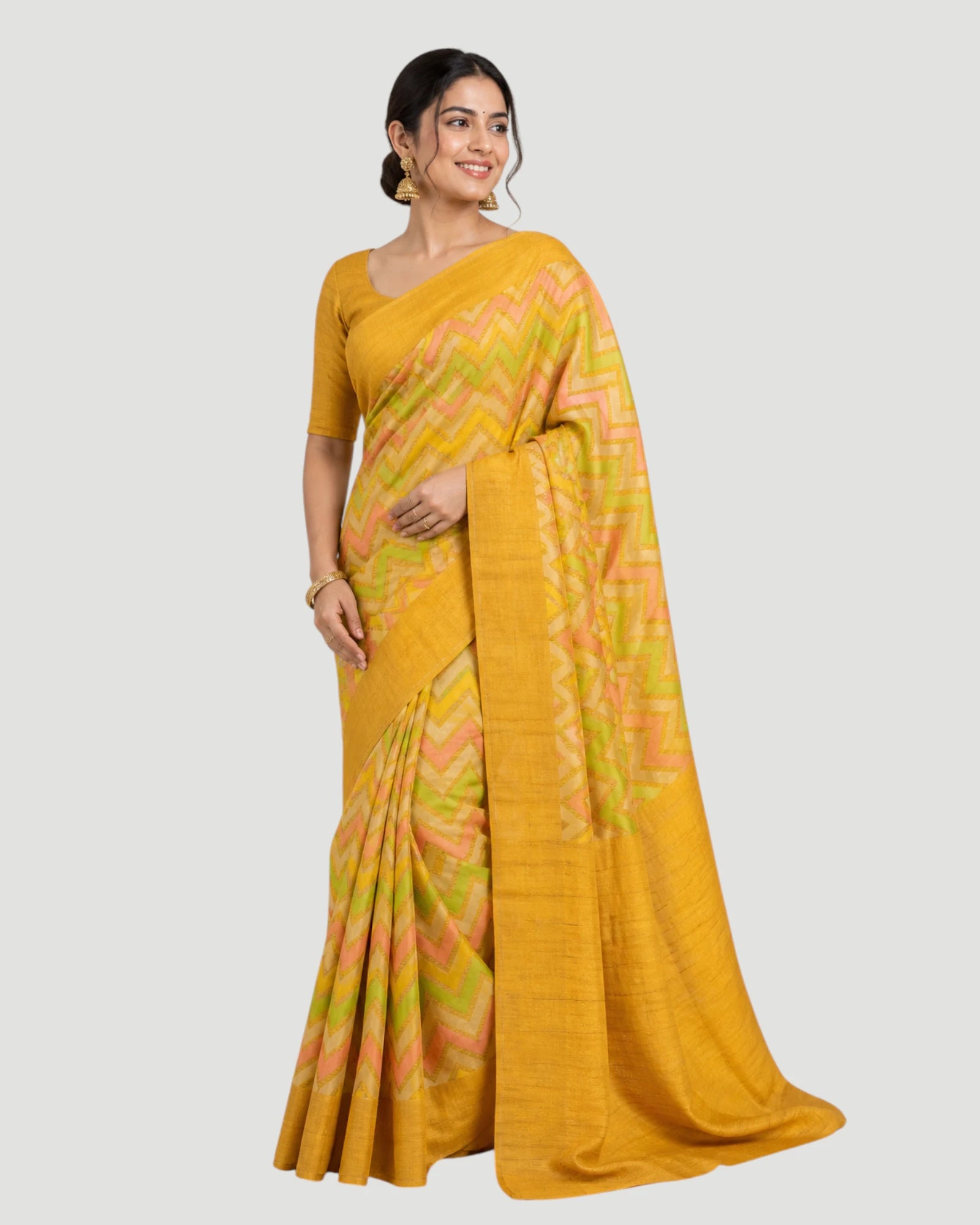 Woman wearing a yellow saree with a subtle pattern on a white background