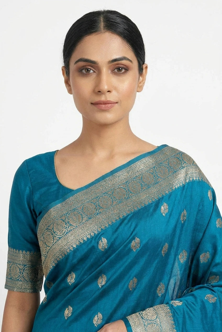 Woman wearing a blue saree with silver patterns on a white background