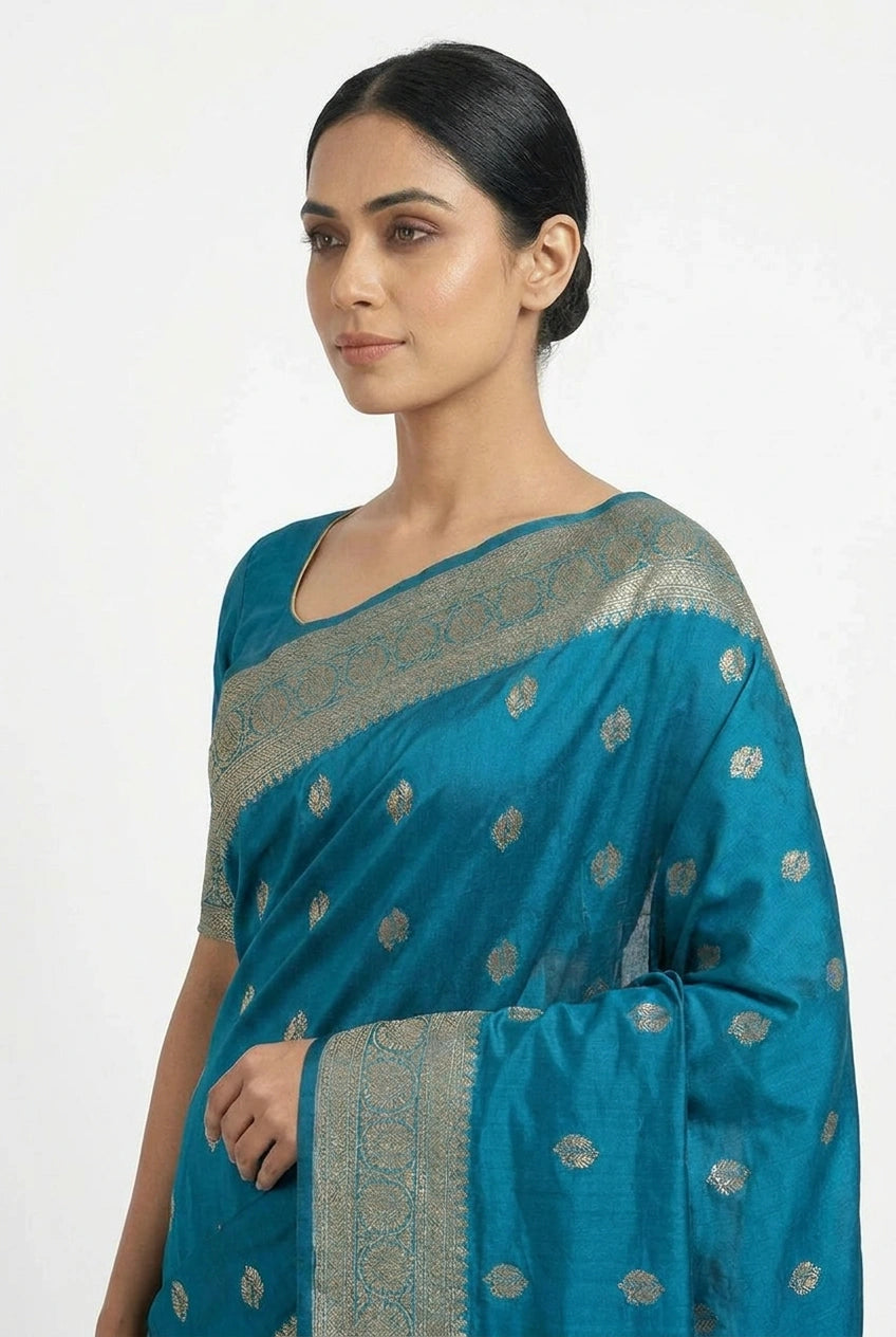 Woman wearing a blue saree with silver patterns on a white background